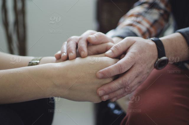 People holding hands in a comforting way